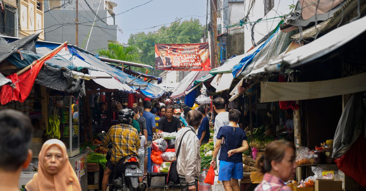 A lively street market scene filled with people and colorful stalls in Southeast Asia.